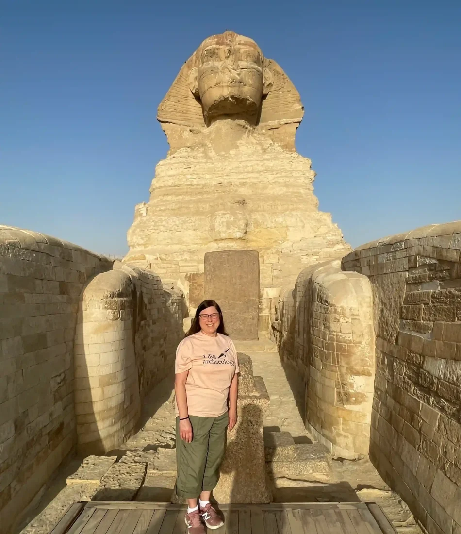 Eye on Egypt Travel guest standing between the paws of the Sphinx