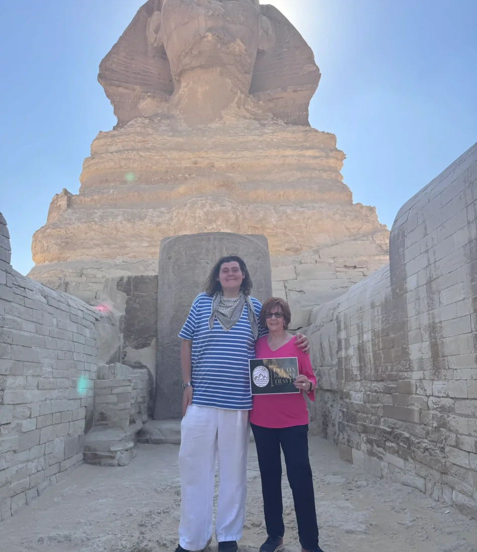 Guests standing between the Paws of the sphinx as a part of our private access to the Sphinx visit